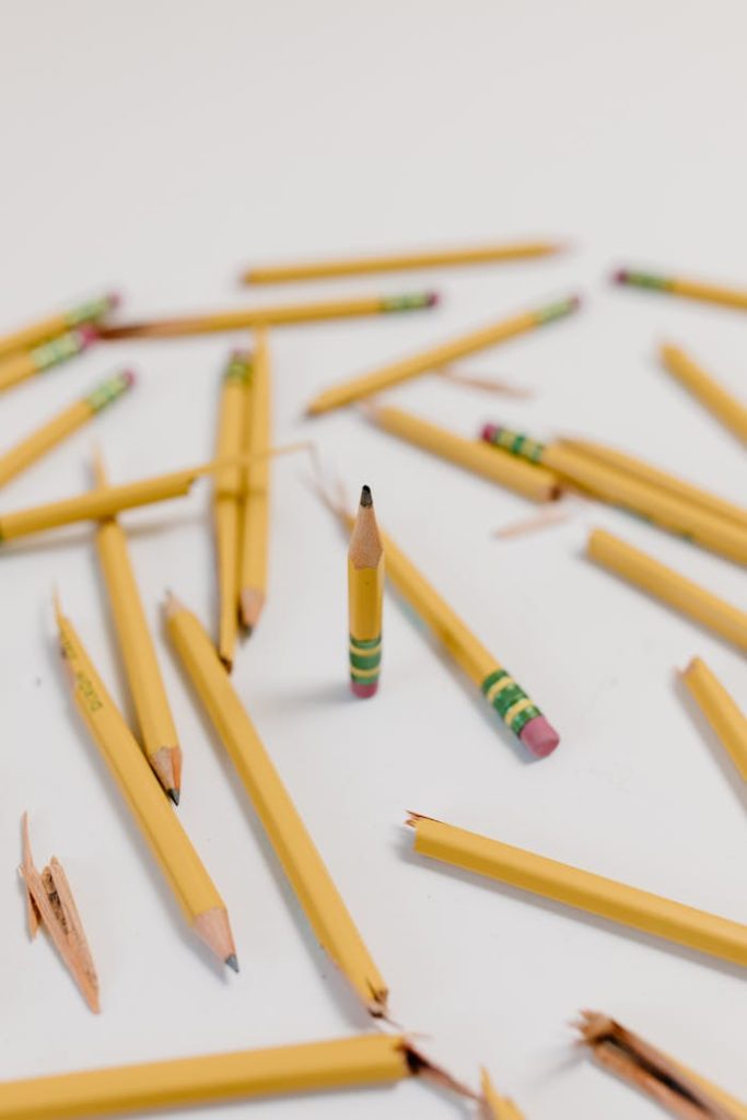 A creatively arranged set of broken and whole yellow pencils on a white background, emphasizing selective focus.